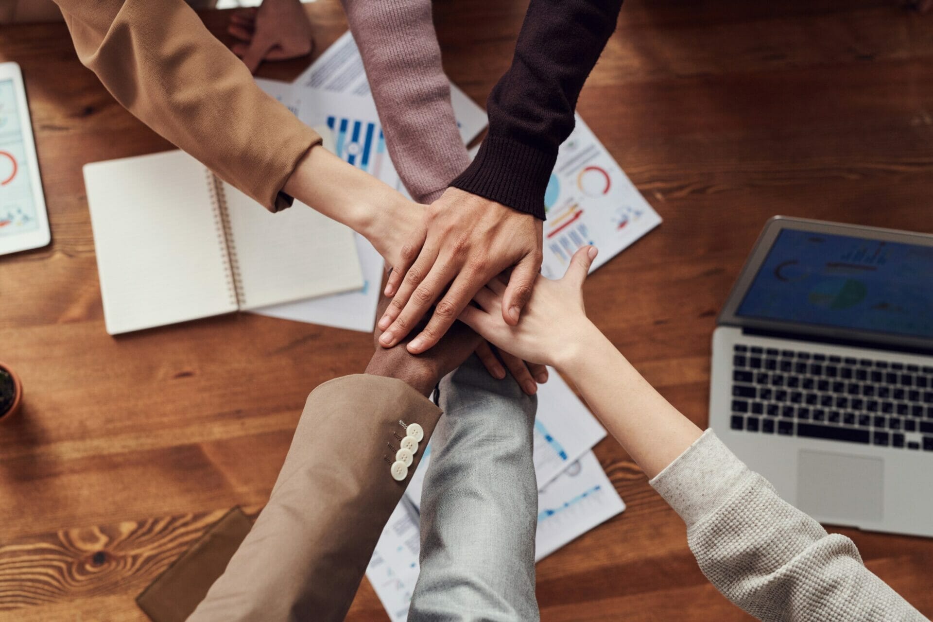 collaboration group hands together Group hold hands together in collaboration over work papers