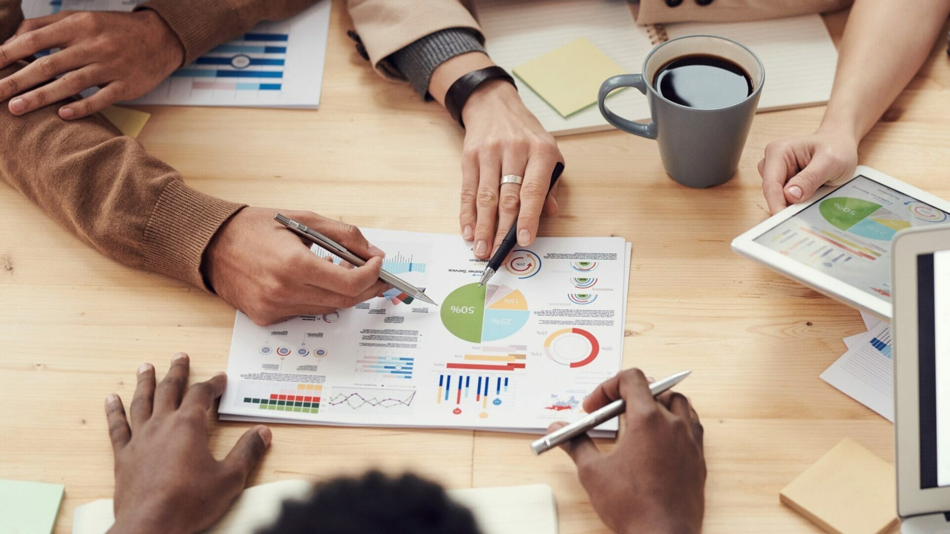 Group of colleagues huddle around a strategy document at board table