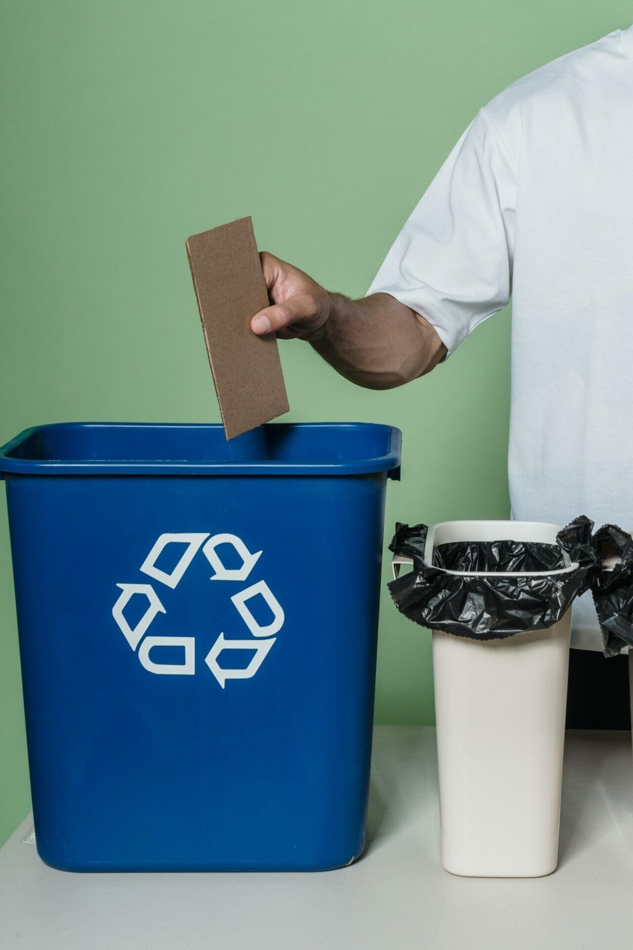 Man placing cardboard into blue plastic recycling bin