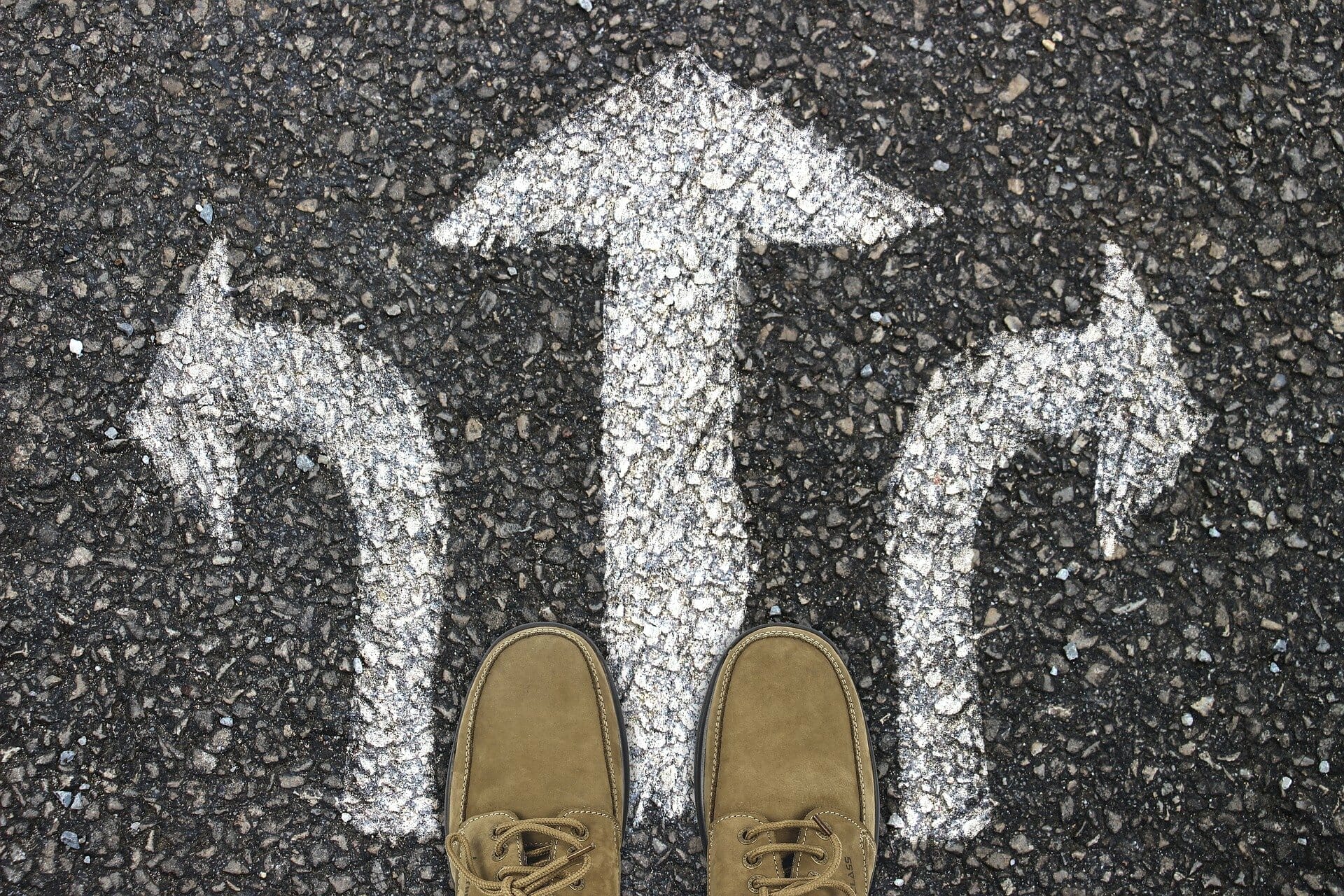 path-g2c941a5a6_1920 Tarmac surface man's shoes. Three painted arrows point, left, right and straight ahead.