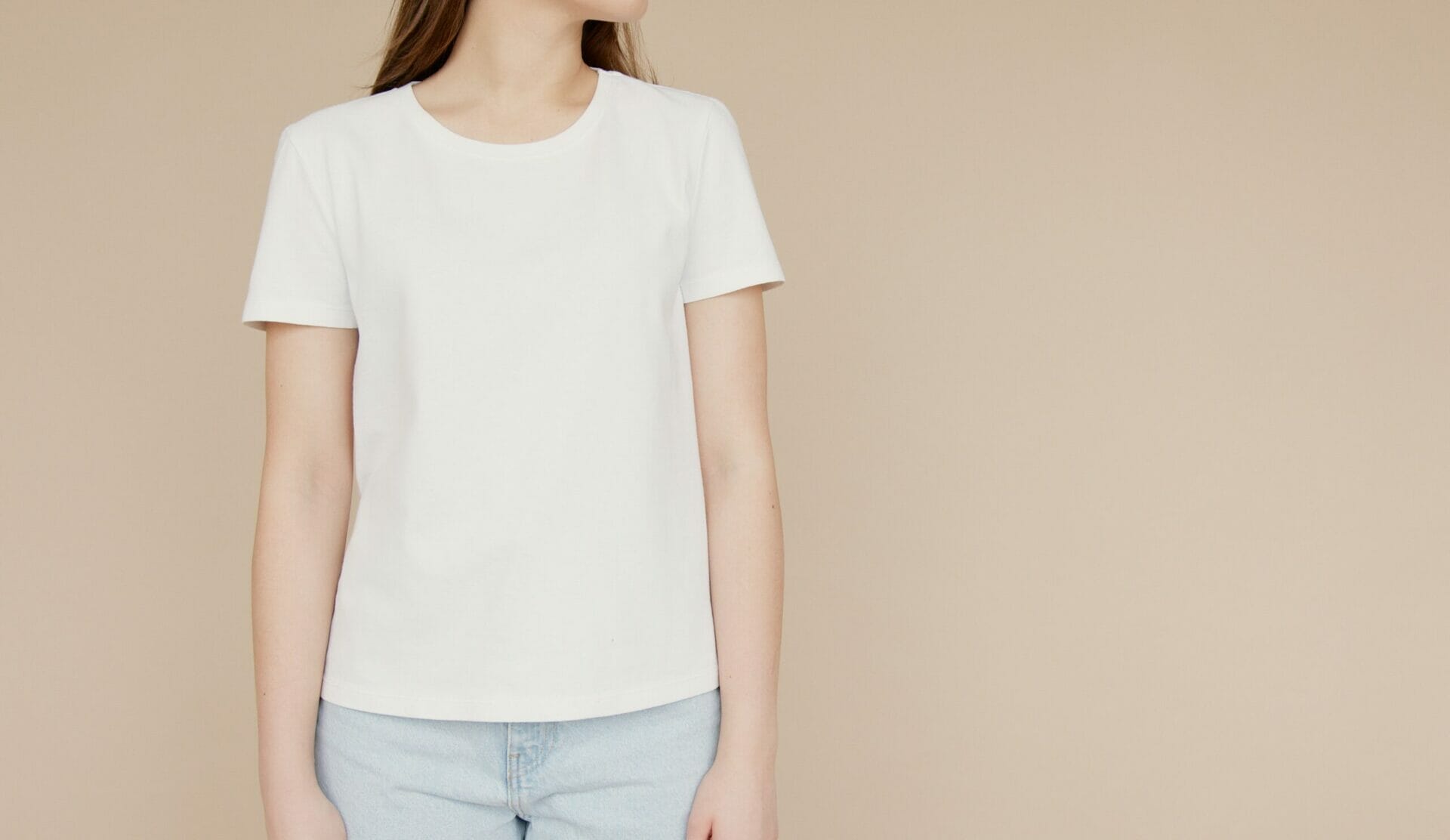 Woman wearing plain white tee shirt with beige wall behind