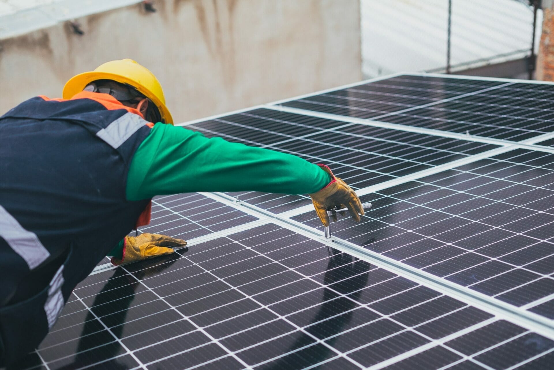technician installs solar panels on building rooftop