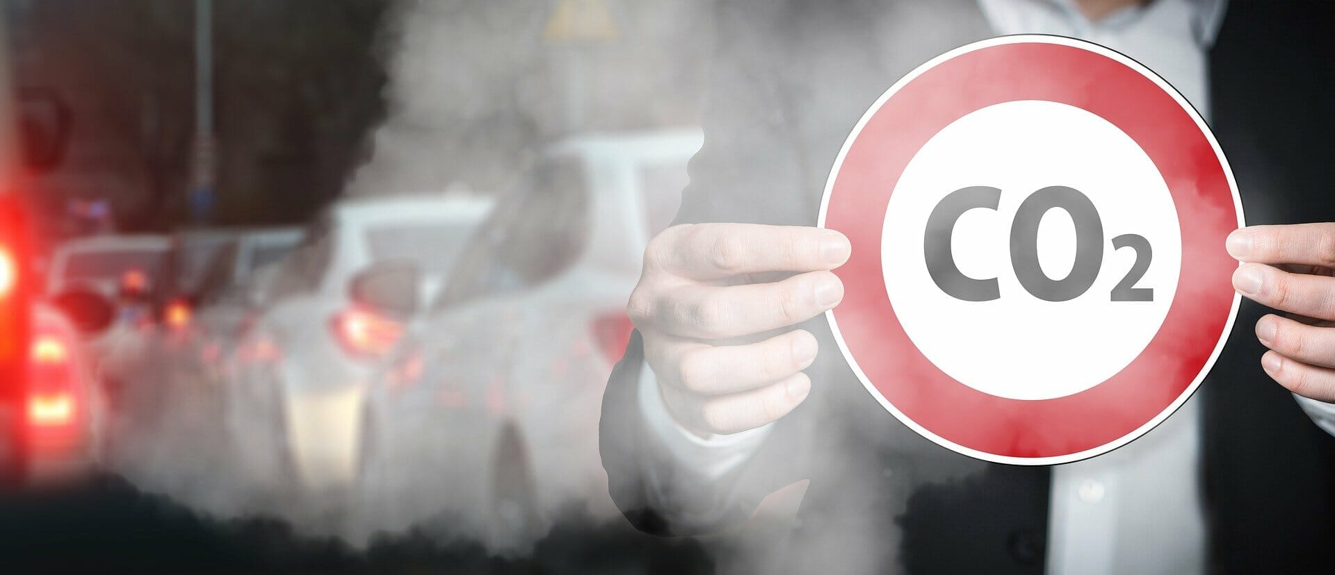tips reduce emissions un Person standing on congested road holding stop sign with CO2 symbol, air is filled with smoke